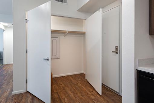 A white door is open to a room with wood flooring.