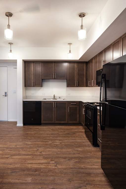 A kitchen with dark wood cabinets and a black refrigerator.