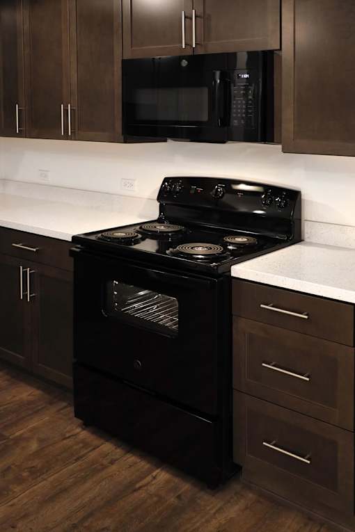 A black stove in a kitchen with wooden cabinets.