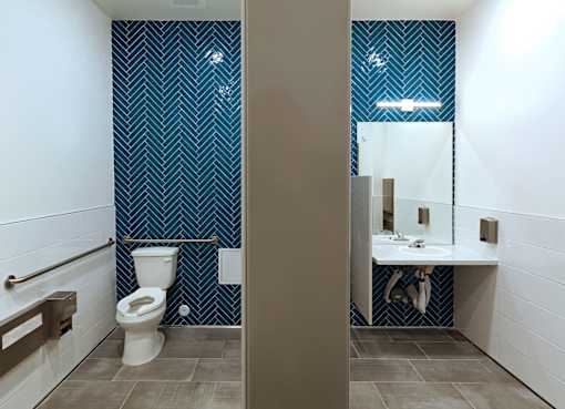 A bathroom with a toilet, sink, and a blue patterned wallpaper.