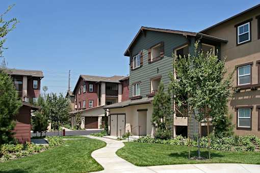 A row of houses with a sidewalk in front.