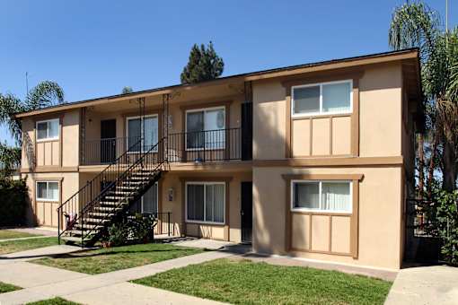 A beige two-story apartment building with a black metal staircase.