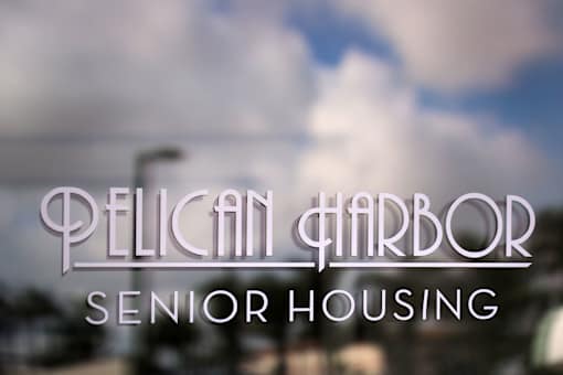 Pelican Harbor Senior Housing logo on a blurred background.