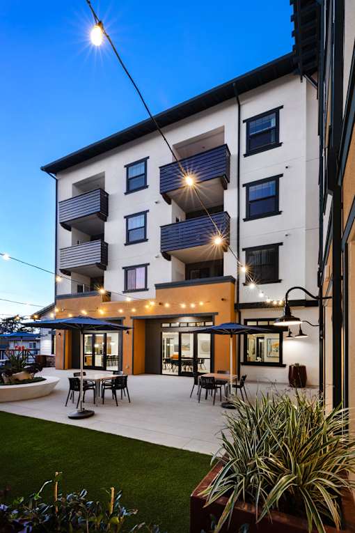 A modern apartment building with a patio and outdoor furniture.