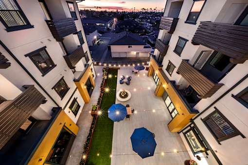 A courtyard with a blue umbrella and lights on the ground.