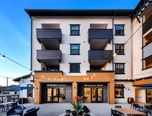 A modern building with a patio and tables.