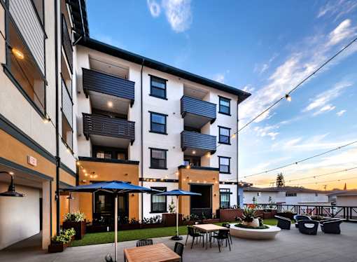 A modern apartment building with a patio area and outdoor furniture.