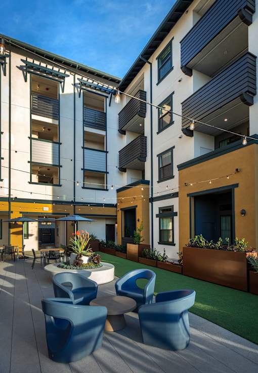 A modern building with a courtyard and blue chairs.
