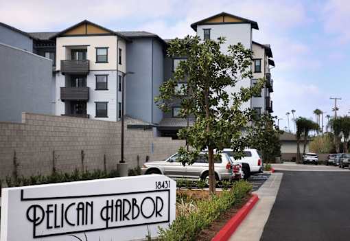 A street view of a residential area with a sign that reads "Pelican Harbor".