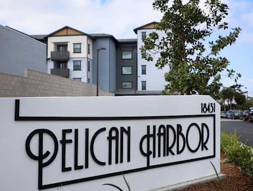 A sign that says Pelican Harbor in front of a building.
