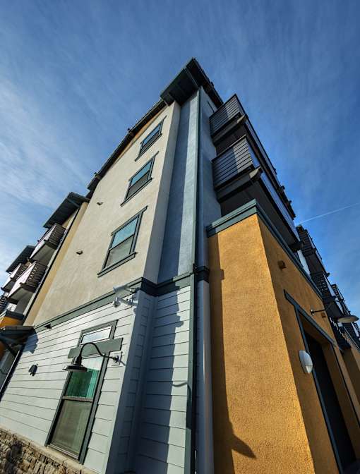 A tall building with a grey and yellow facade stands under a blue sky.