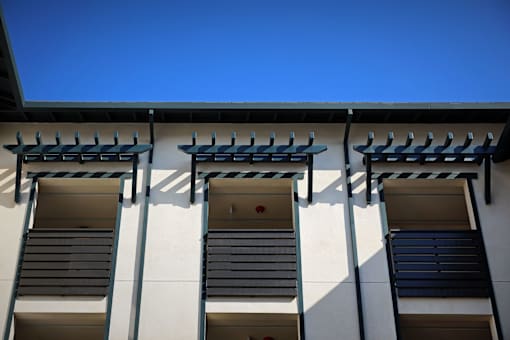 Three windows with black shutters on a white building.