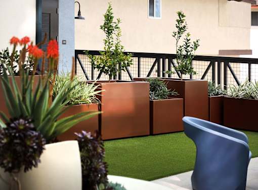 A balcony with a blue chair and a planter with purple flowers.