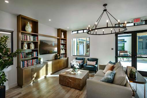 A living room with a large bookshelf and a chandelier.
