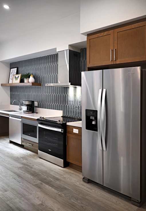 A modern kitchen with a stainless steel refrigerator and wooden cabinets.