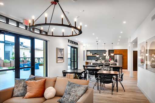 A modern living room with a large chandelier and a couch with multiple pillows.