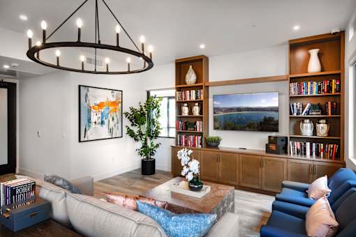 A living room with a large sofa, a coffee table, a bookshelf, and a painting on the wall.