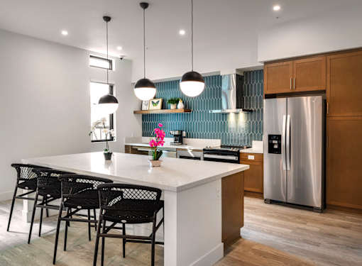 A kitchen with a white countertop and black chairs.