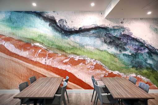 A room with a large mural of a beach scene and a table with chairs.
