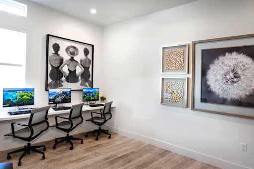 A room with a desk, chairs, and artwork on the wall.