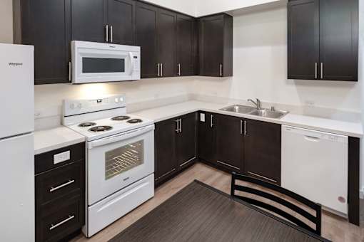 A kitchen with black cabinets and white appliances.