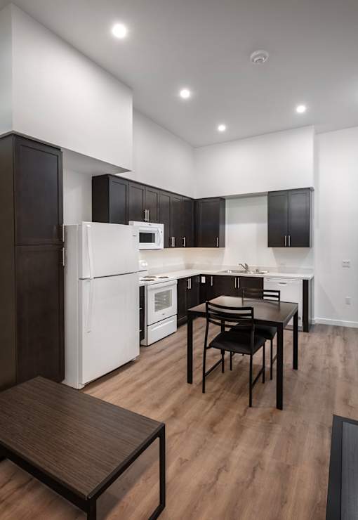 A modern kitchen with a white refrigerator and black cabinets.