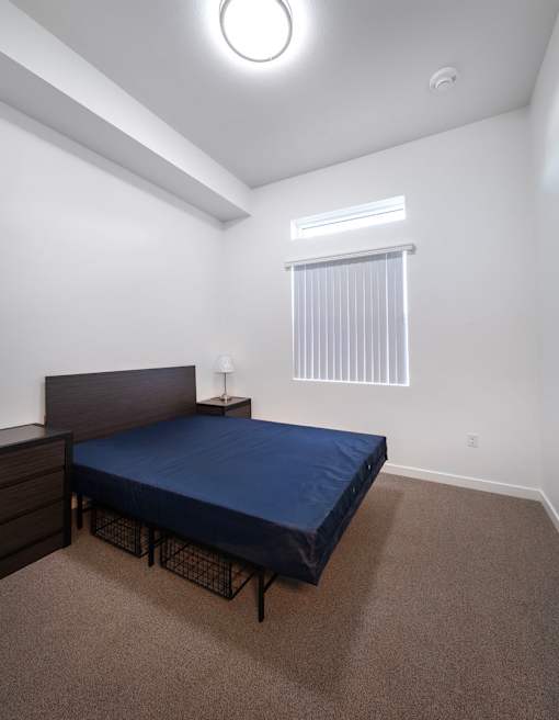 A bedroom with a bed, nightstand, and window.