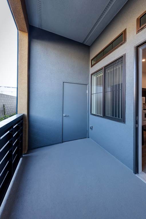 A room with a grey floor and a grey wall with a door and a window.