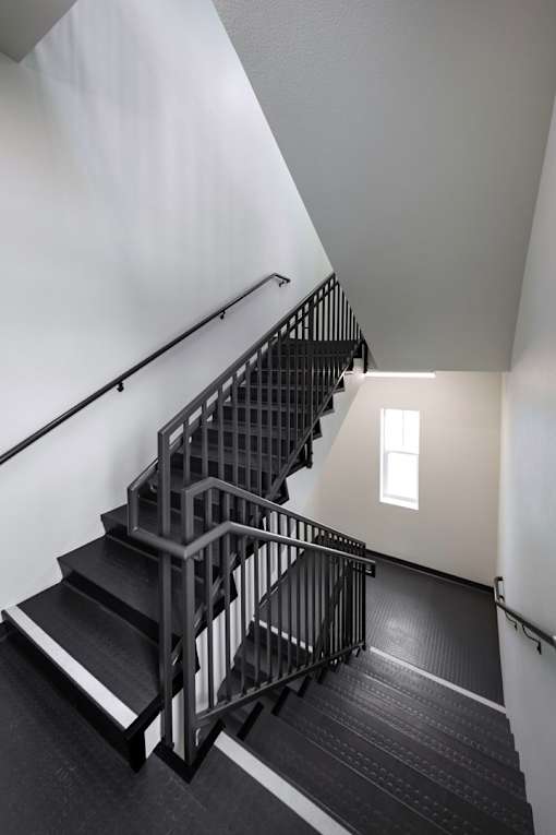 A staircase with a metal railing and black steps.