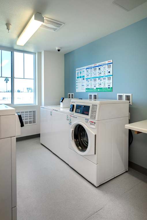 A large washing machine is in a room with a monitor on the wall.