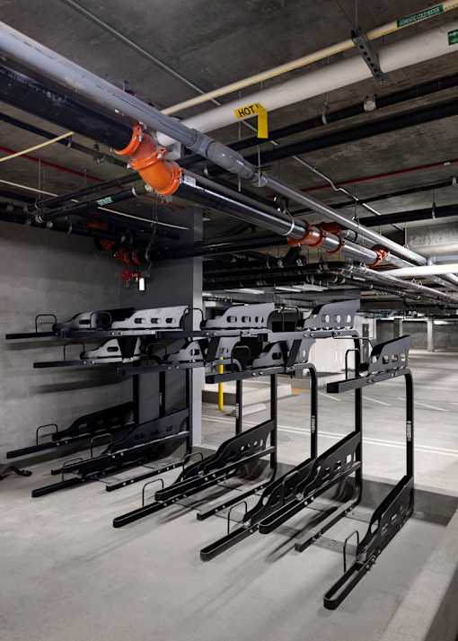 A parking garage with a row of black bikes on the racks.
