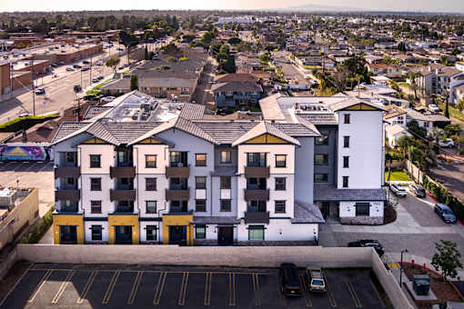 A large white and yellow building with a parking lot in front.
