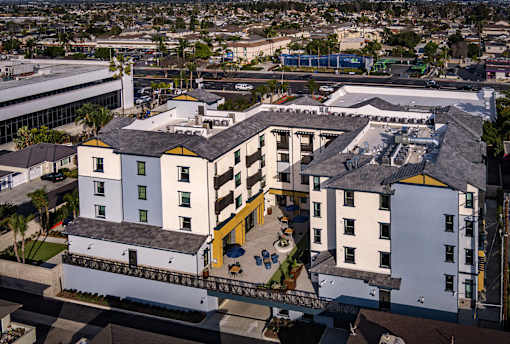 A white building with a yellow awning is in the foreground of a cityscape.