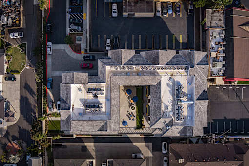 An aerial view of a building with a white facade and a red car parked in front.