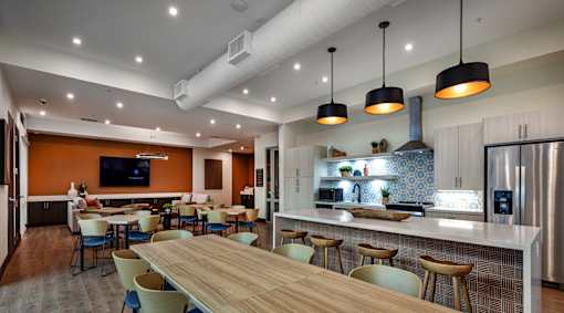 A modern kitchen with a long wooden table and chairs.