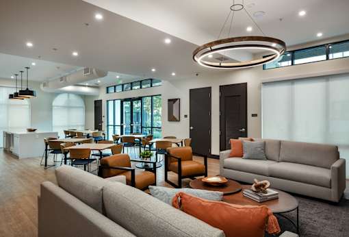 A modern living room with a grey sofa and orange pillows.