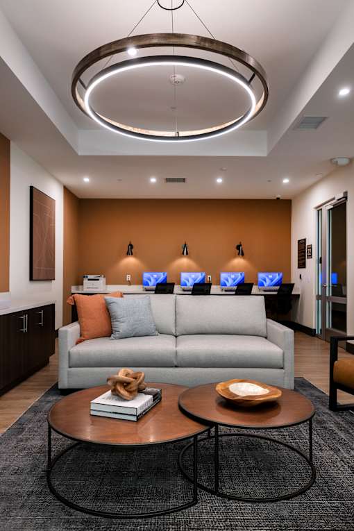 A modern living room with a grey sofa, a coffee table, and a large circular light fixture on the ceiling.