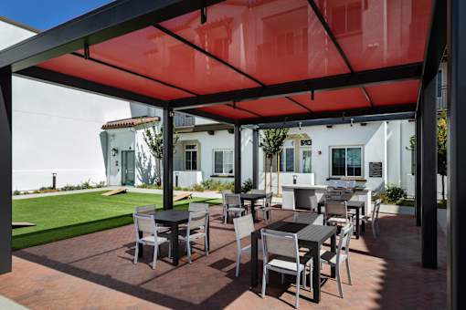 A patio with a table and chairs under a red canopy.