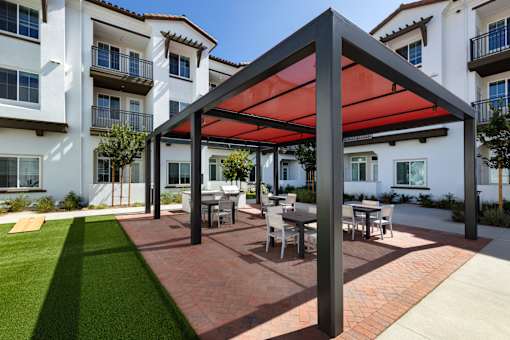 A patio with a table and chairs under a red canopy.