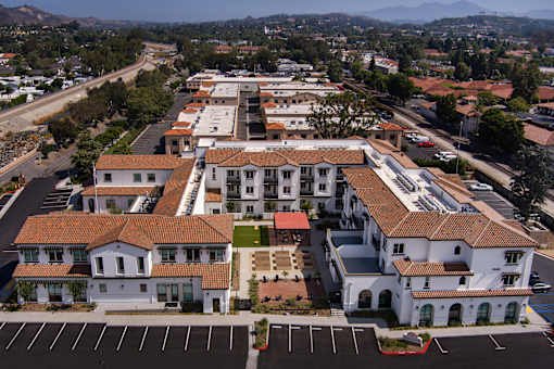 A large white building with a red roof is surrounded by parking lots.