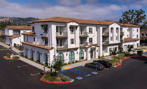 A parking lot in front of a white apartment building.