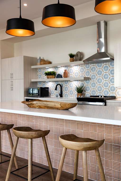 A kitchen with a white counter top and wooden stools.