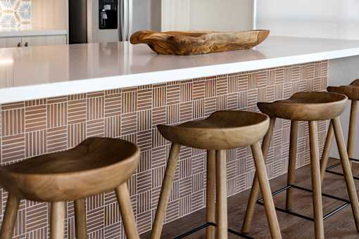 Four wooden bar stools in front of a bar counter.
