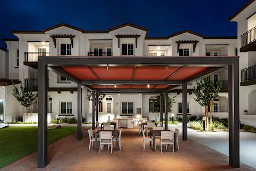 A patio with a table and chairs is illuminated by lights under a canopy.