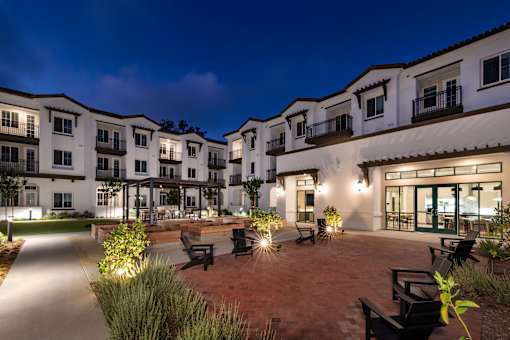 A courtyard with benches and plants is surrounded by apartment buildings.