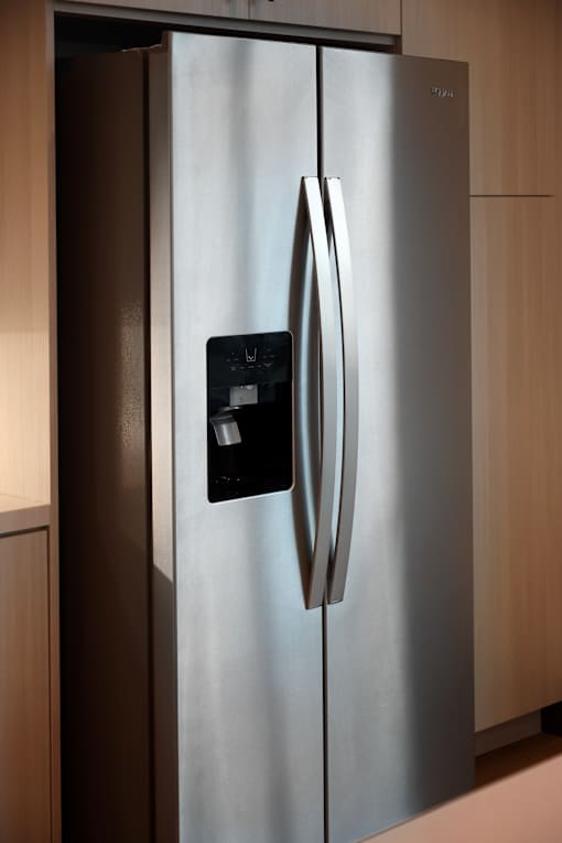 A stainless steel refrigerator with a black control panel on the door.