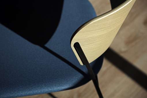 A blue chair with a wooden backrest and black metal legs.