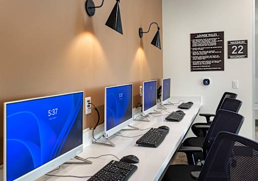 A row of computers are lined up on a white desk.
