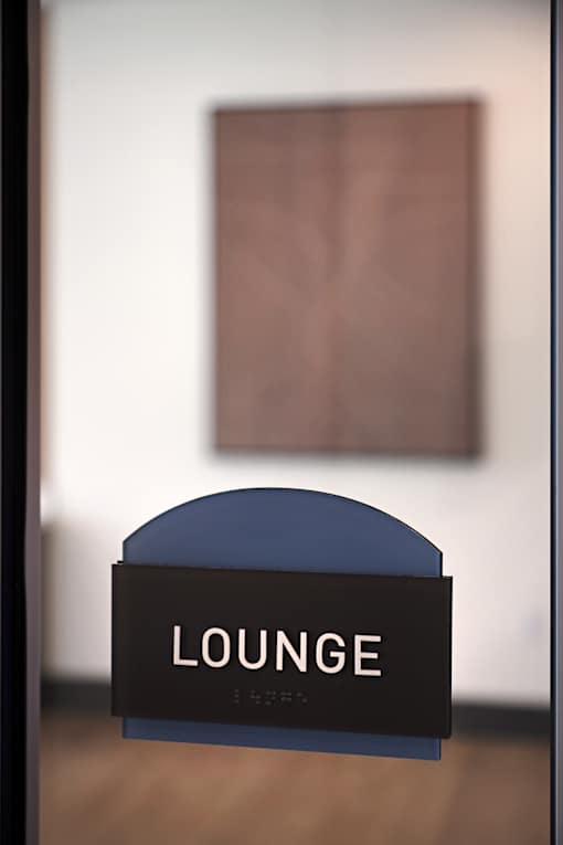 A sign that says "LOUNGE" is in front of a painting.