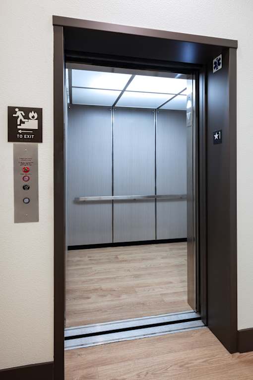 A black door with a sign on the wall to the left of the door.